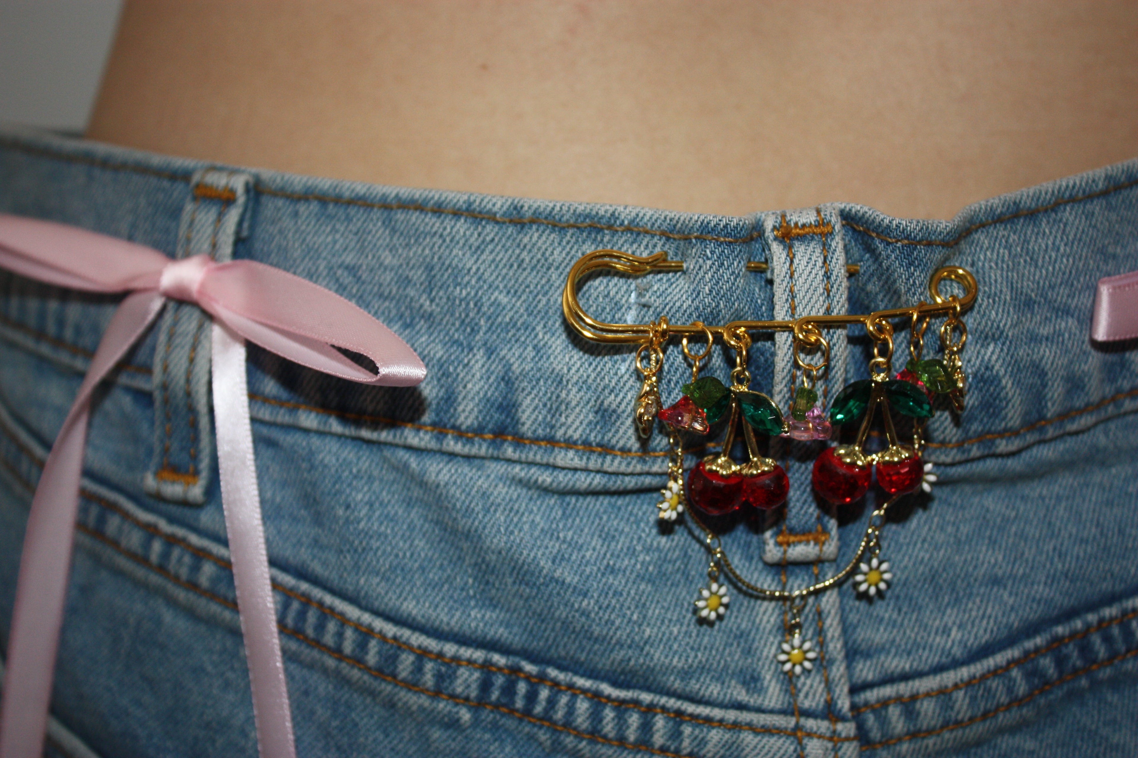 Denim jacket adorned with gold charm pins.